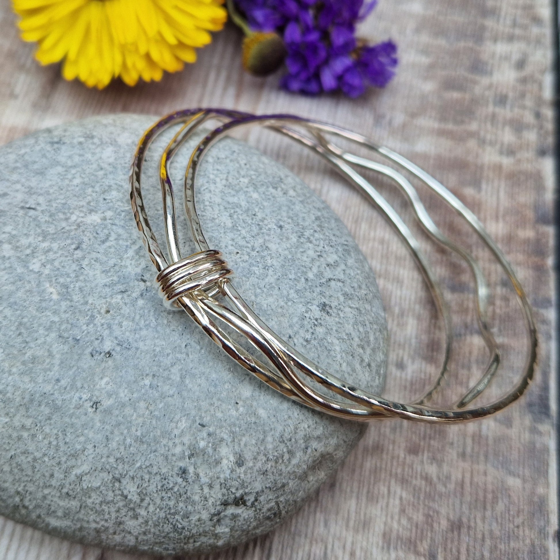 Three sterling silver bangles with hammered texture, centre bangle is wavy. Bangles are joined by three oval shaped links.