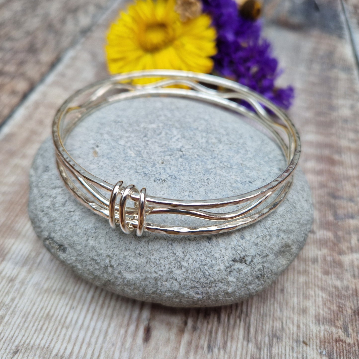 Three sterling silver bangles with hammered texture, centre bangle is wavy. Bangles are joined by three oval shaped links.