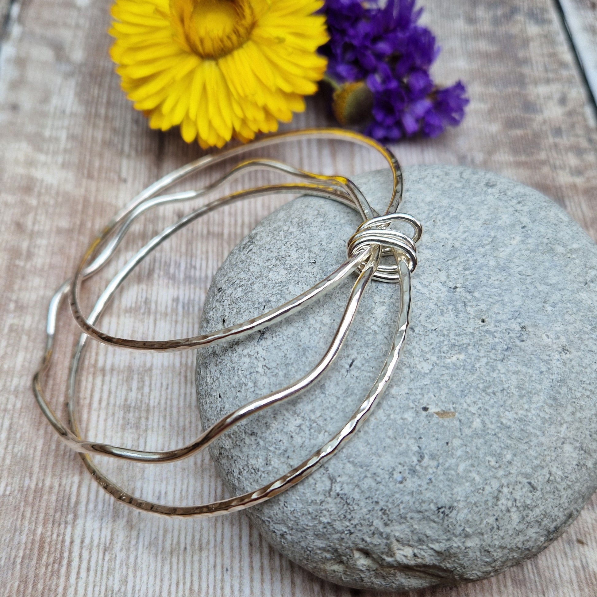 Three sterling silver bangles with hammered texture, centre bangle is wavy. Bangles are joined by three oval shaped links.