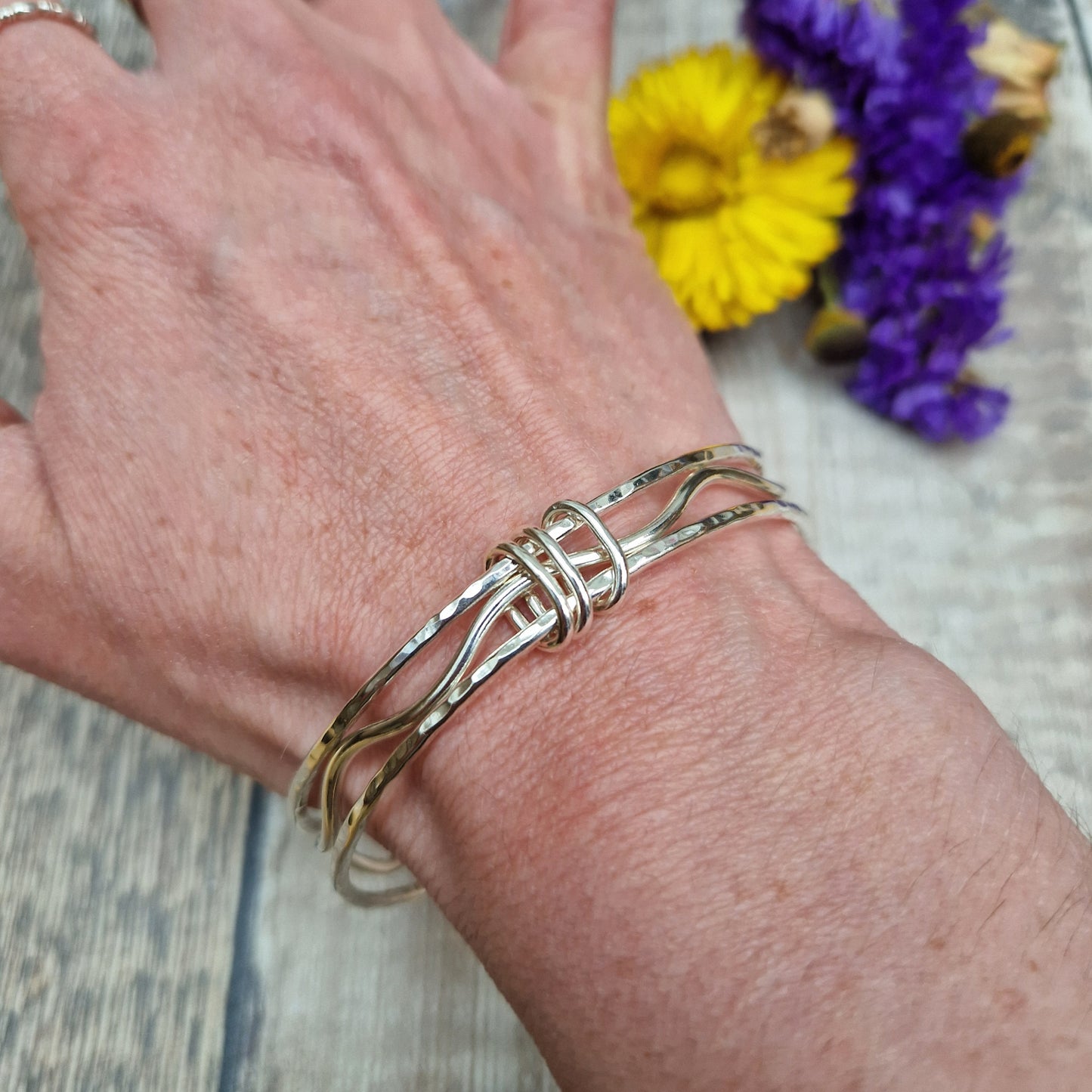 Three sterling silver bangles with hammered texture, centre bangle is wavy. Bangles are joined by three oval shaped links.