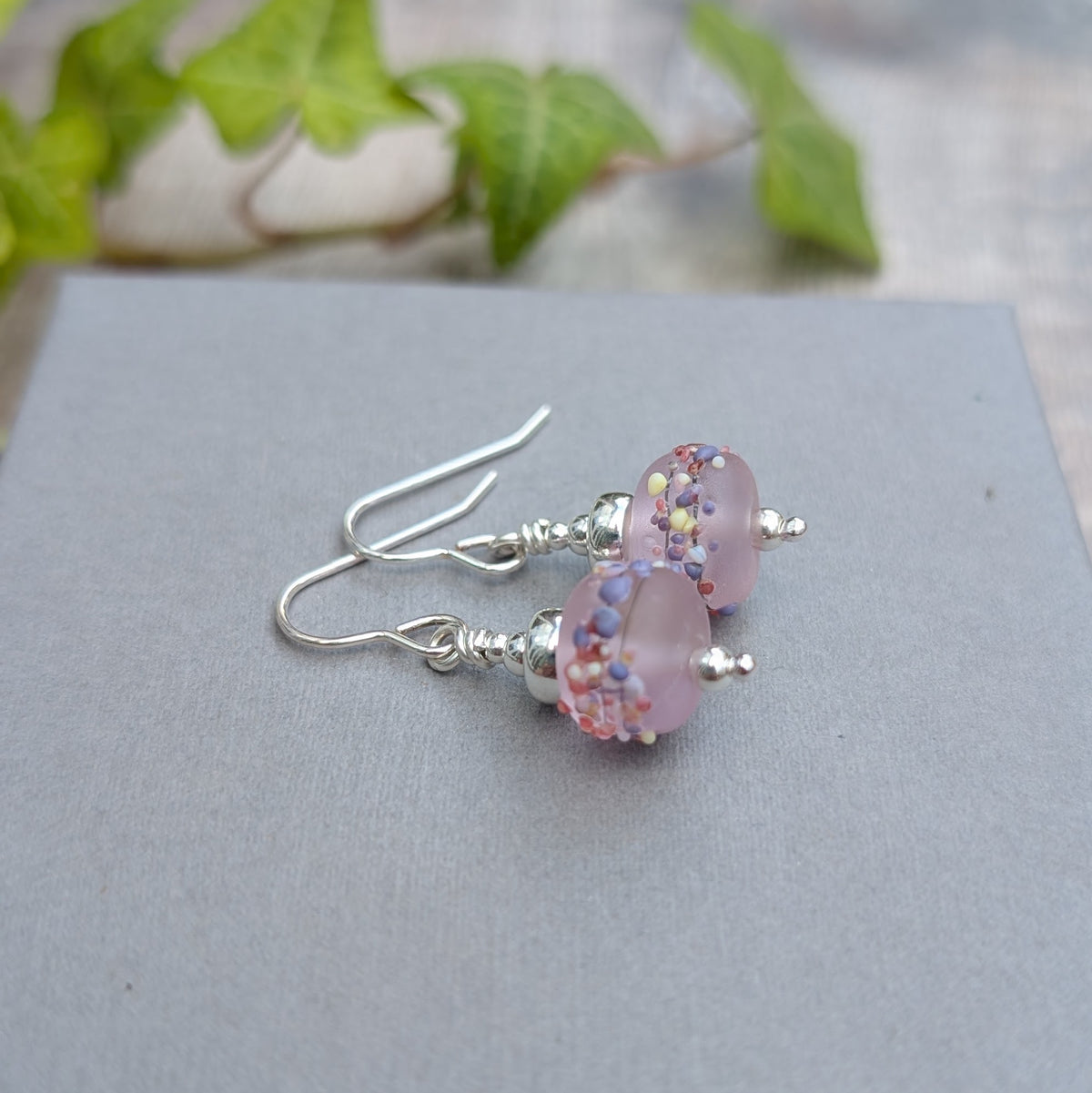 Pair of Tropical Pink Lampwork Glass Earrings with handmade frosted pink glass beads and recycled Sterling Silver, photographed on a grey background.