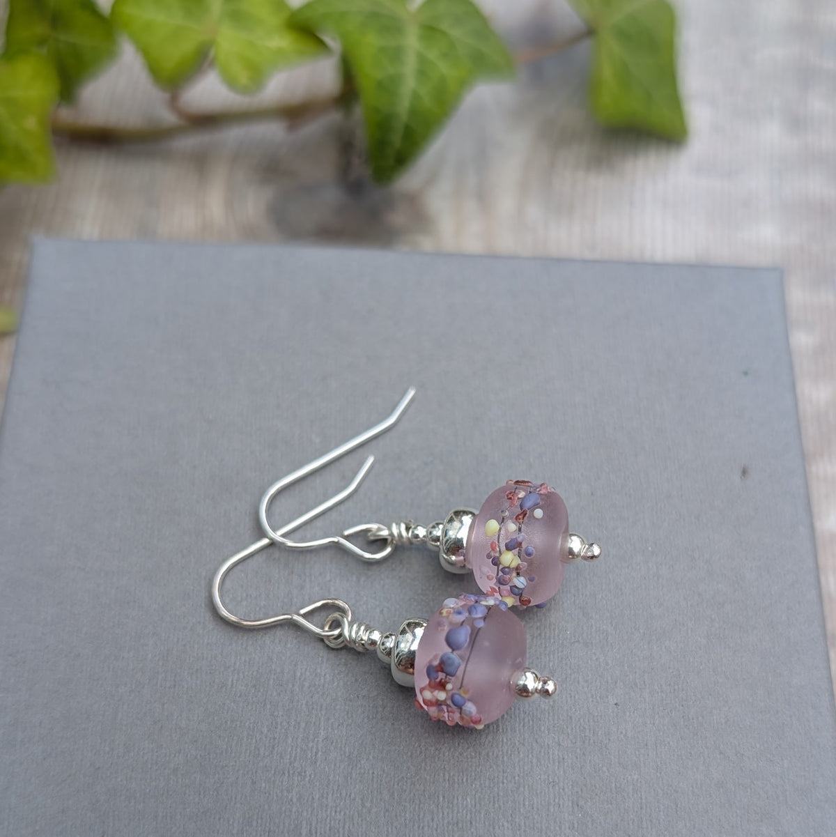Tropical Pink Lampwork Glass Earrings handmade from recycled Sterling Silver with frosted pink handmade glass beads, displayed on a grey background.
