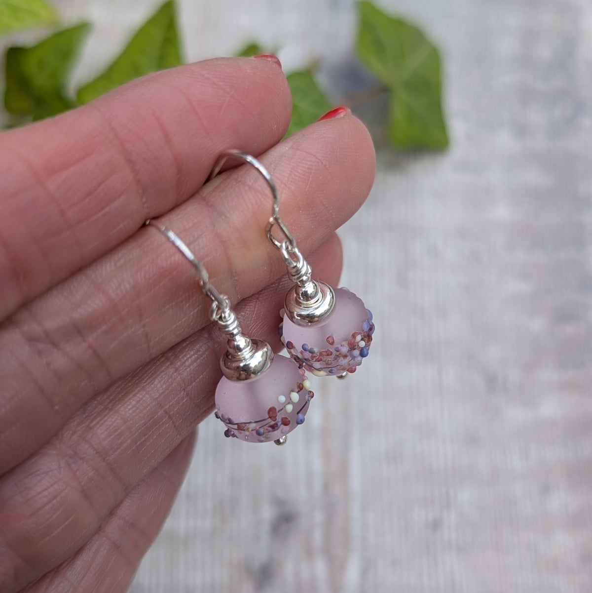 Close up of Tropical Pink Lampwork Glass Earrings held in a hand, showing the frosted finish and colourful details on the handmade Lampwork beads.