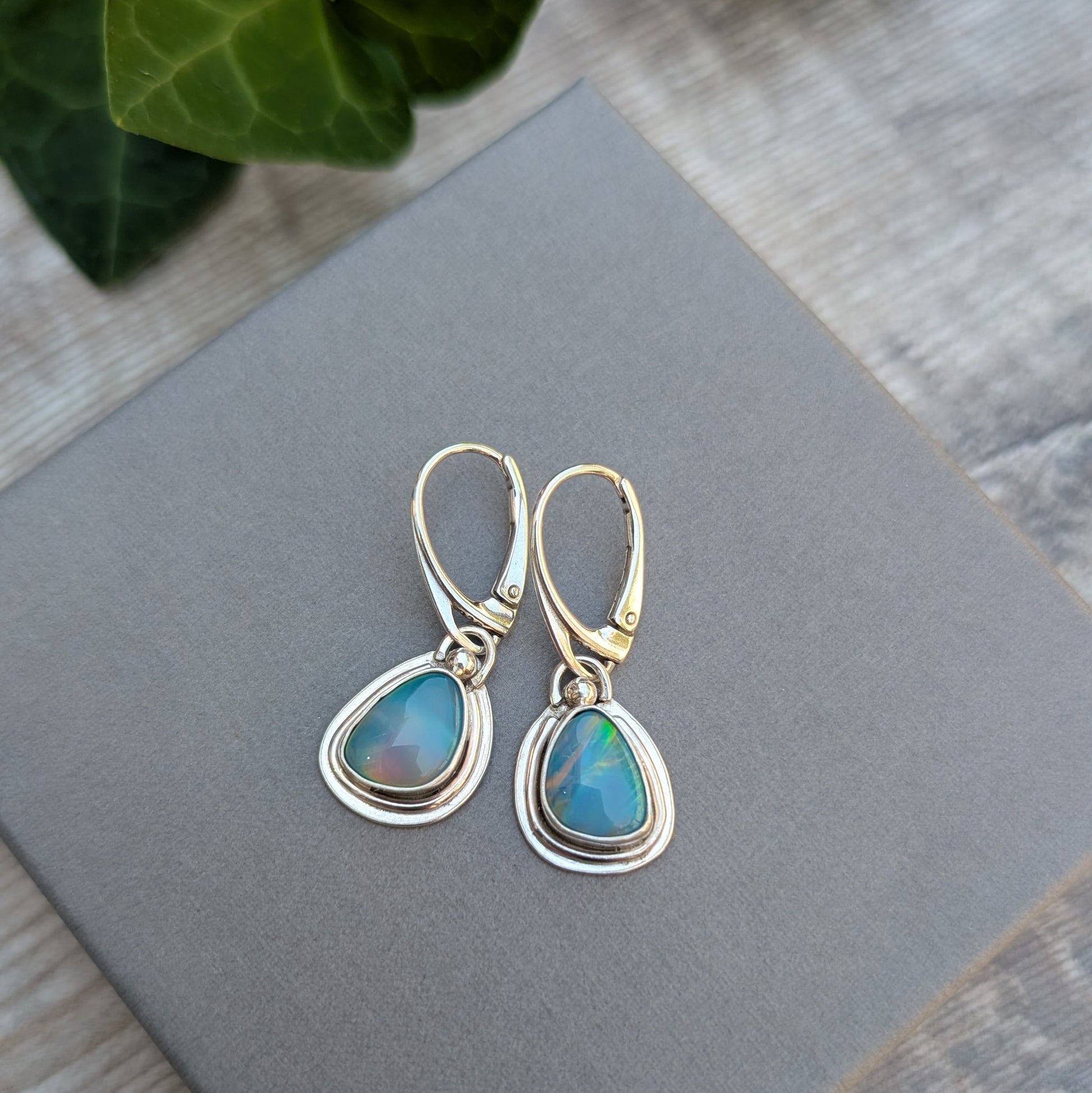 Turquoise Blue Aurora Opal Teardrop Earrings handmade from recycled Sterling Silver, displayed on a grey jewellery box highlighting the vibrant Aurora Opal stones.