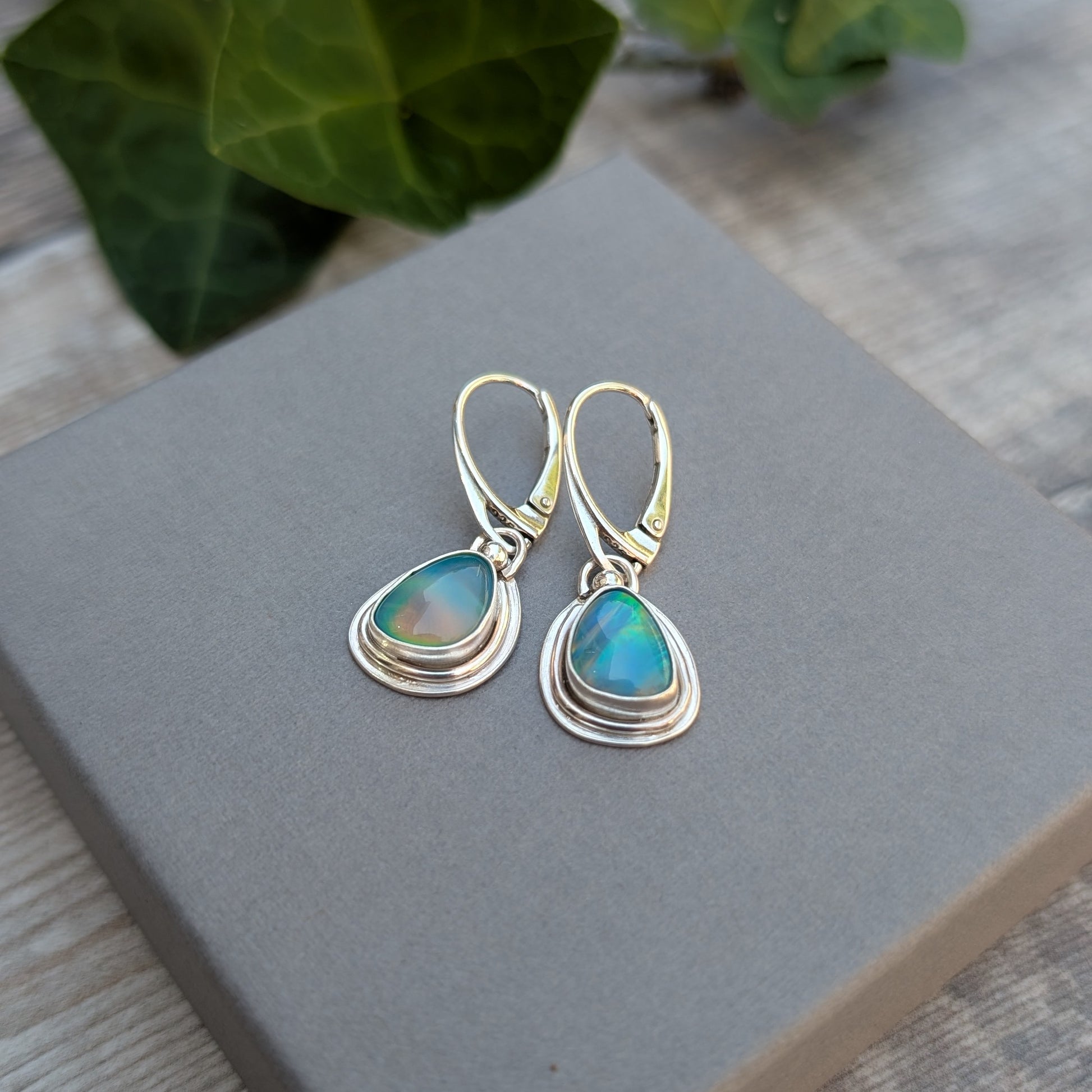 Turquoise Blue Aurora Opal Teardrop Earrings handmade from recycled Sterling Silver, displayed on a grey jewellery box highlighting the vibrant Aurora Opal stones.