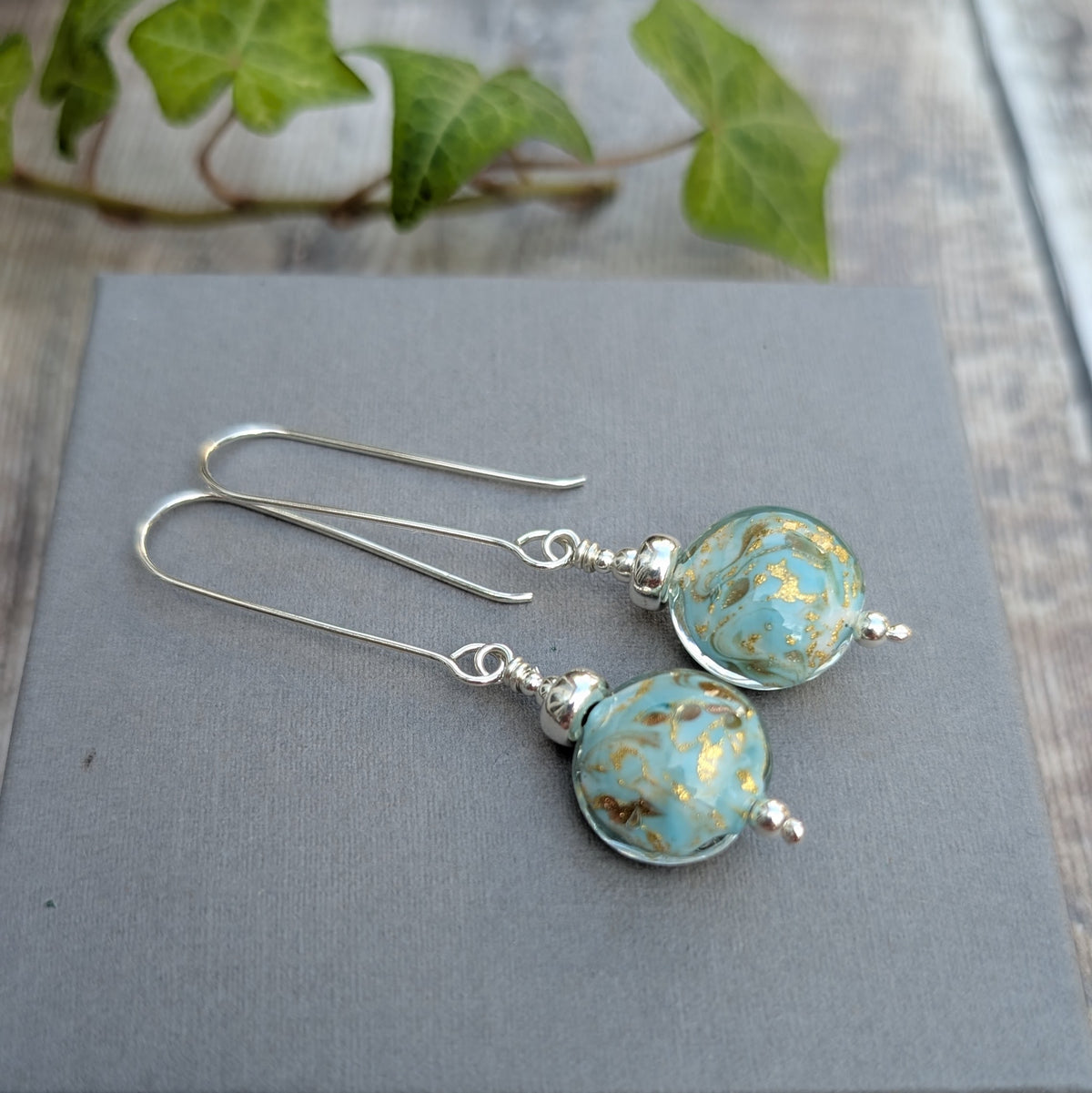 turquoise marbled Venetian glass long silver earrings handmade from recycled sterling silver with round turquoise and gold lampwork glass beads, displayed on a grey background.