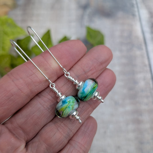Watercolour Lampwork Glass Long Earrings held in a hand to show the size and colourful handmade Lampwork glass beads.
