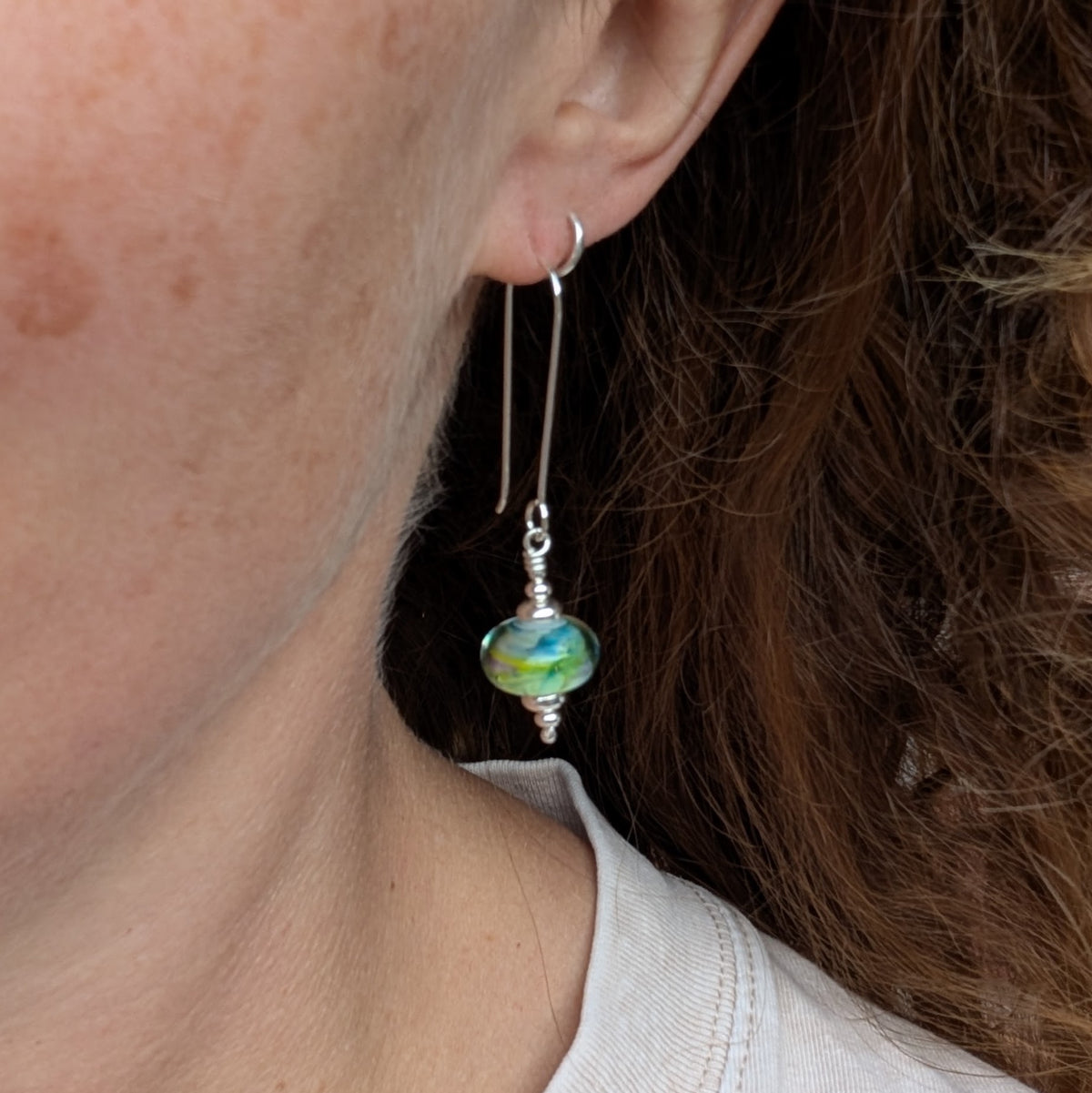 Watercolour Lampwork Glass Long Earrings being worn, showing the length of the silver ear wire and colourful glass bead.
