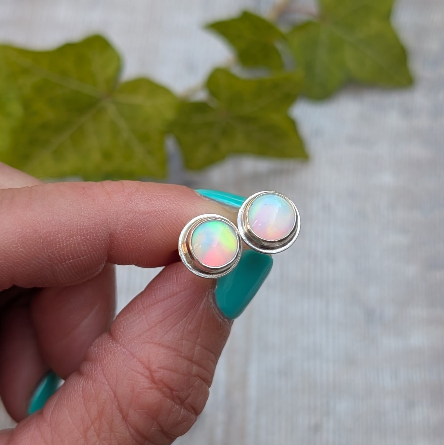 White aurora opal stud earrings handmade from recycled Sterling Silver, shown close up to highlight the colourful flashes of the Aurora Opals.