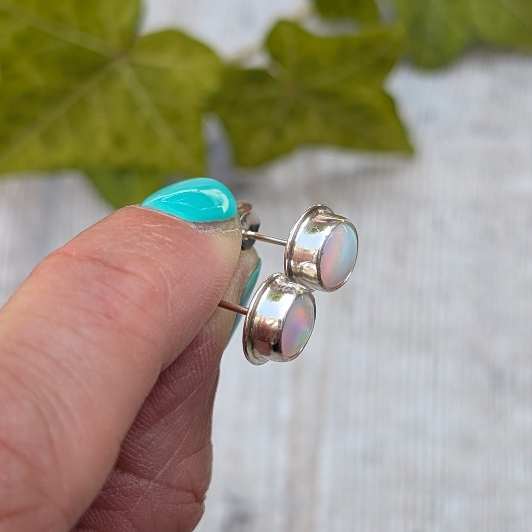 Side view of white aurora opal stud earrings handmade from recycled Sterling Silver, showing the bezel setting and sterling silver posts.
