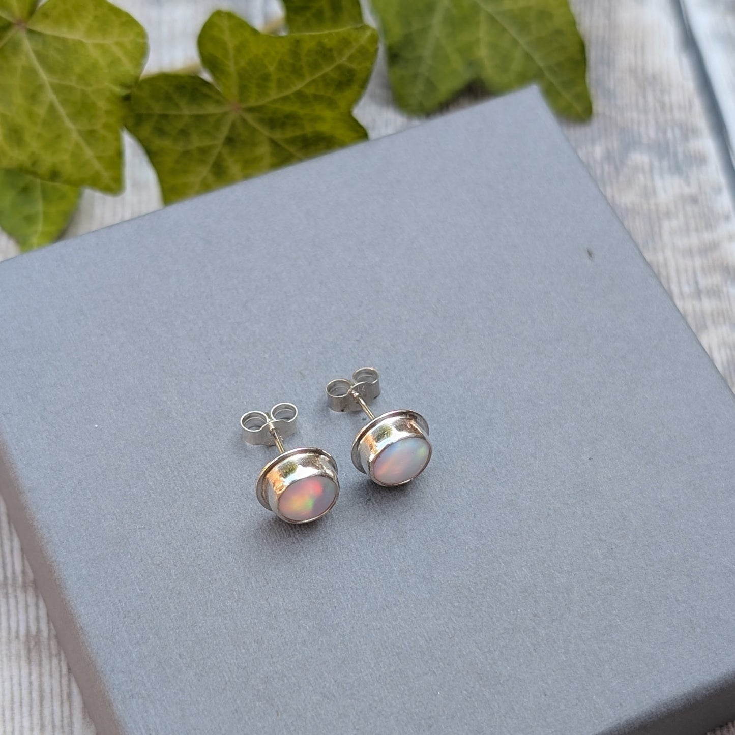 Rear angle of white aurora opal stud earrings handmade from recycled Sterling Silver, showing the sterling silver posts and butterfly backs.