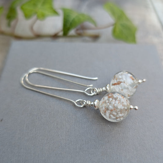 Close up of white aventurina Venetian glass long silver earrings with handmade white and gold Lampwork glass beads on long silver ear wires.