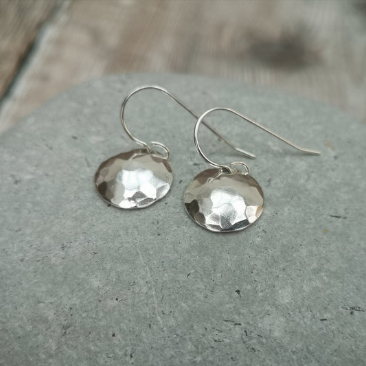 Each earring is a Sterling Silver disc shaped into an outward facing dome with hammered texture finish attached to silver earring wire.