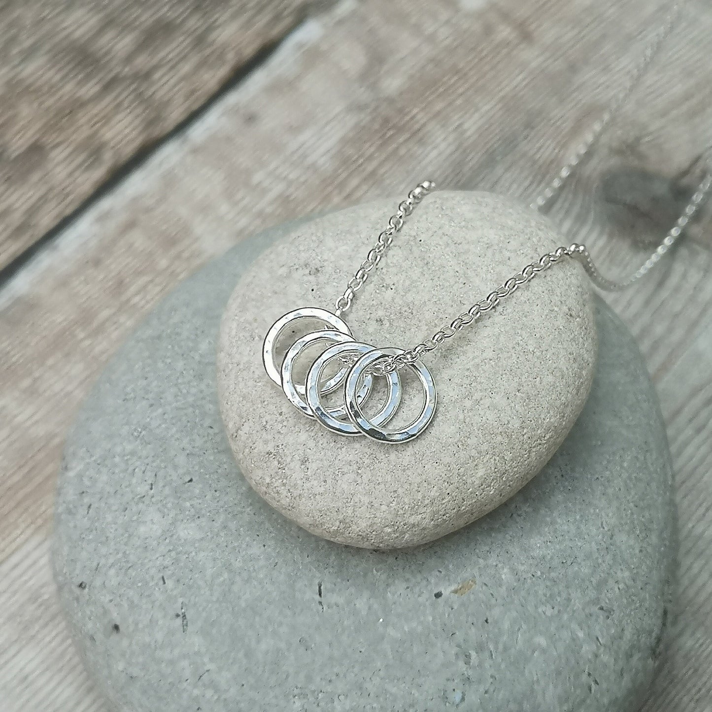 Four Sterling Silver hammered finish open circles threaded through a silver chain.