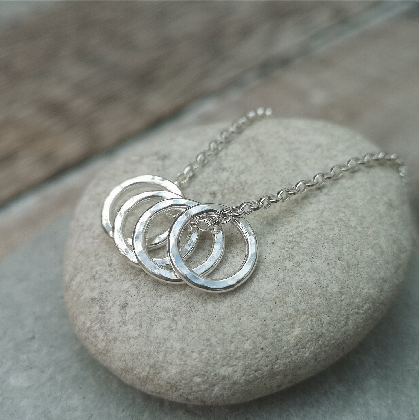 Four Sterling Silver hammered finish open circles threaded through a silver chain.