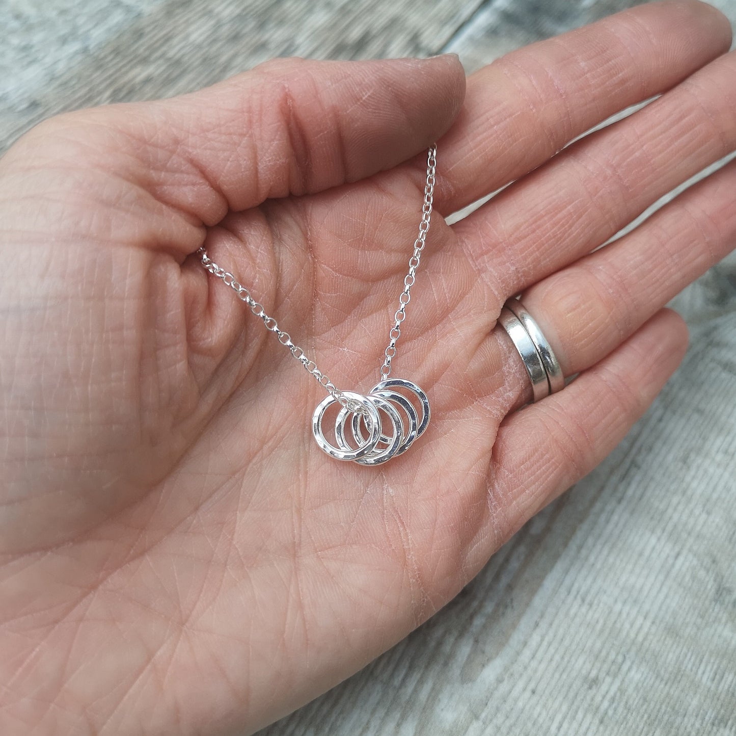 Four Sterling Silver hammered finish open circles threaded through a silver chain.