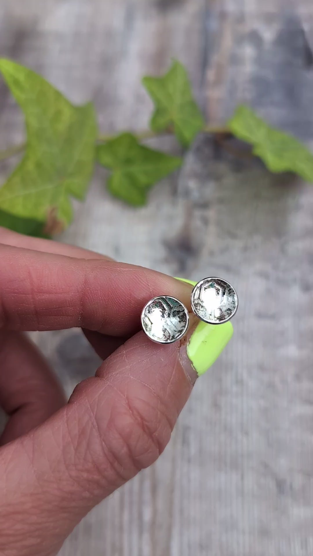 Video of silver honeycomb disc stud earrings held between fingers, showing the honeycomb pattern pressed into the recycled Sterling Silver.