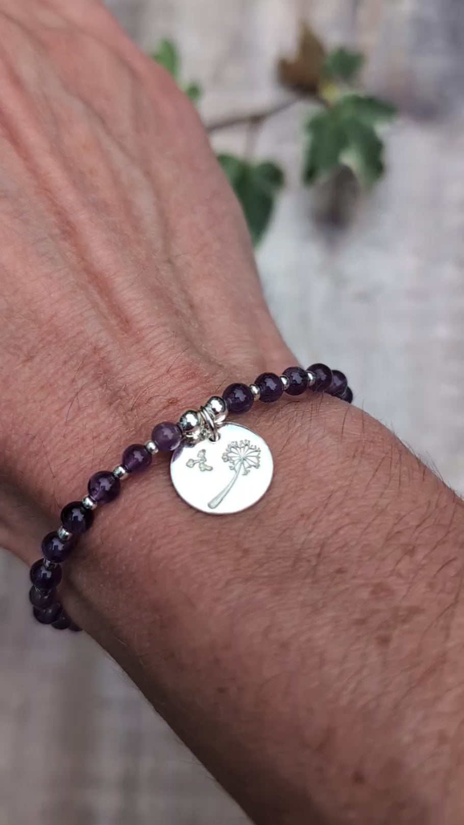 Video of Amethyst and silver dandelion disc bracelet being worn on a wrist, showing the purple amethyst beads and round sterling silver dandelion charm.