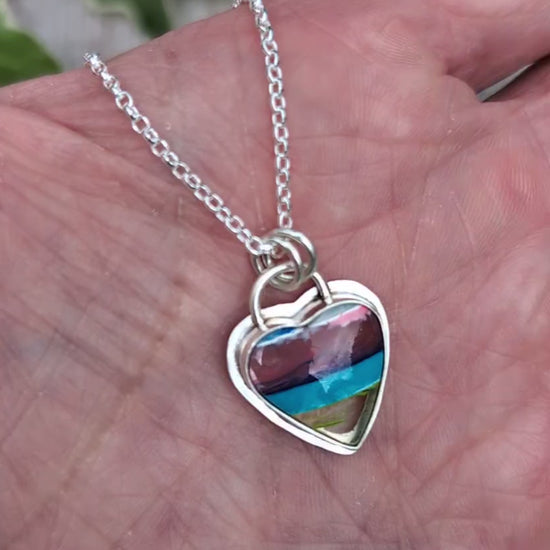 Video of Silver Multicoloured Surfite Heart Necklace held in a hand, showing the handmade silver setting and colourful layered Surfite.