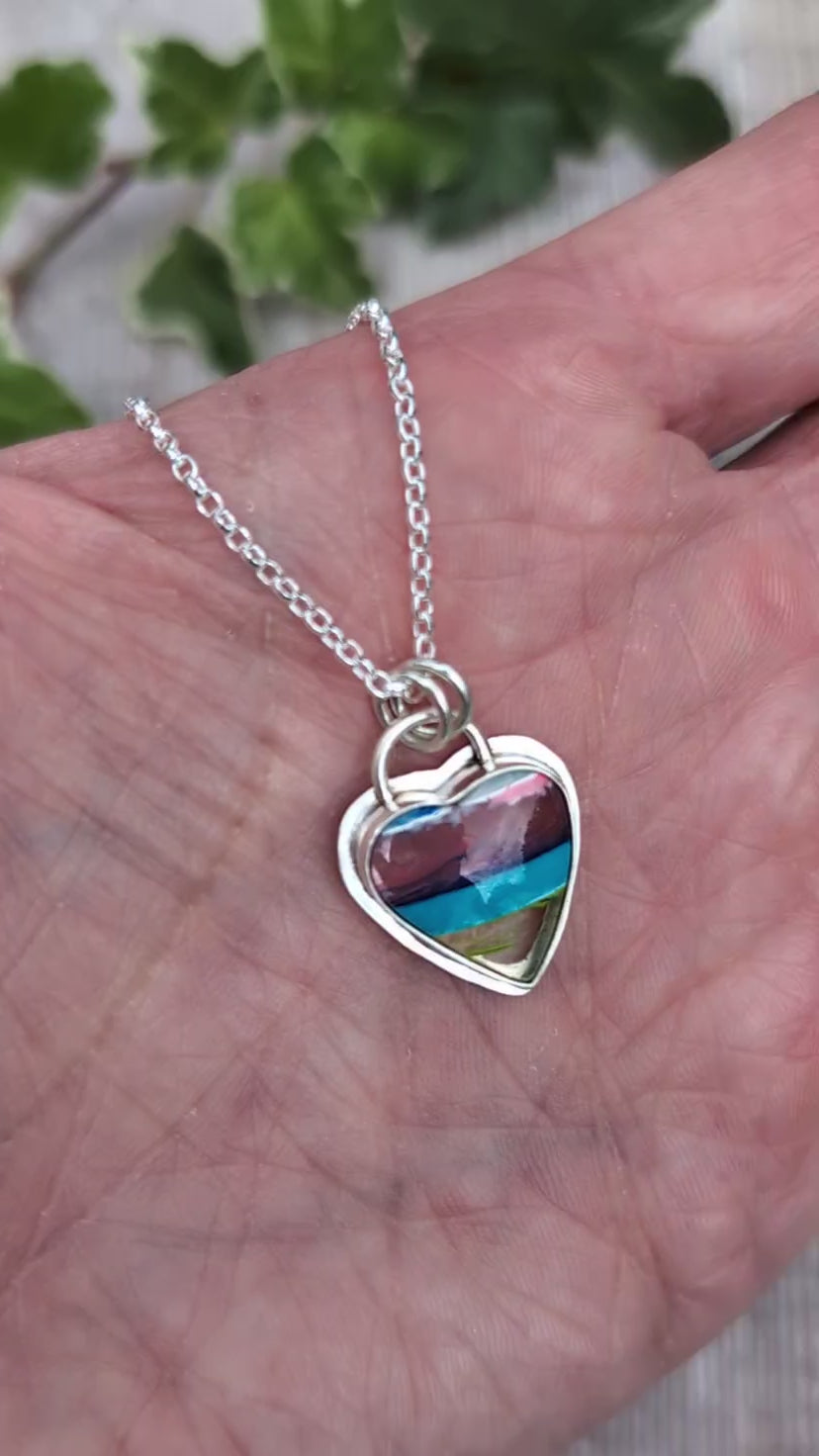 Video of Silver Multicoloured Surfite Heart Necklace held in a hand, showing the handmade silver setting and colourful layered Surfite.
