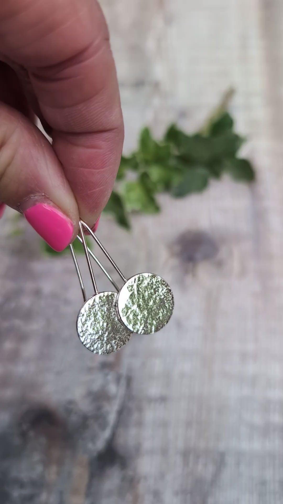 Video of Silver organic disc long earrings held up by their ear wires, showing the uneven organic texture on the recycled Sterling Silver discs.