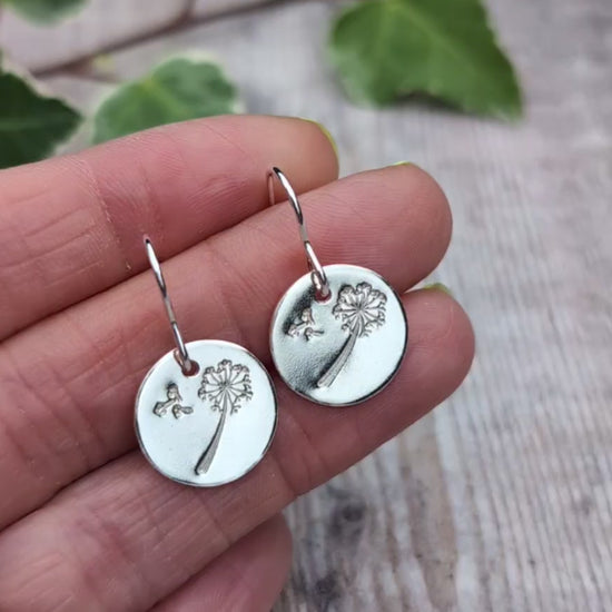 Video of Silver dandelion and wishes disc earrings held in a hand, showing the recycled Sterling Silver discs and stamped dandelion design.