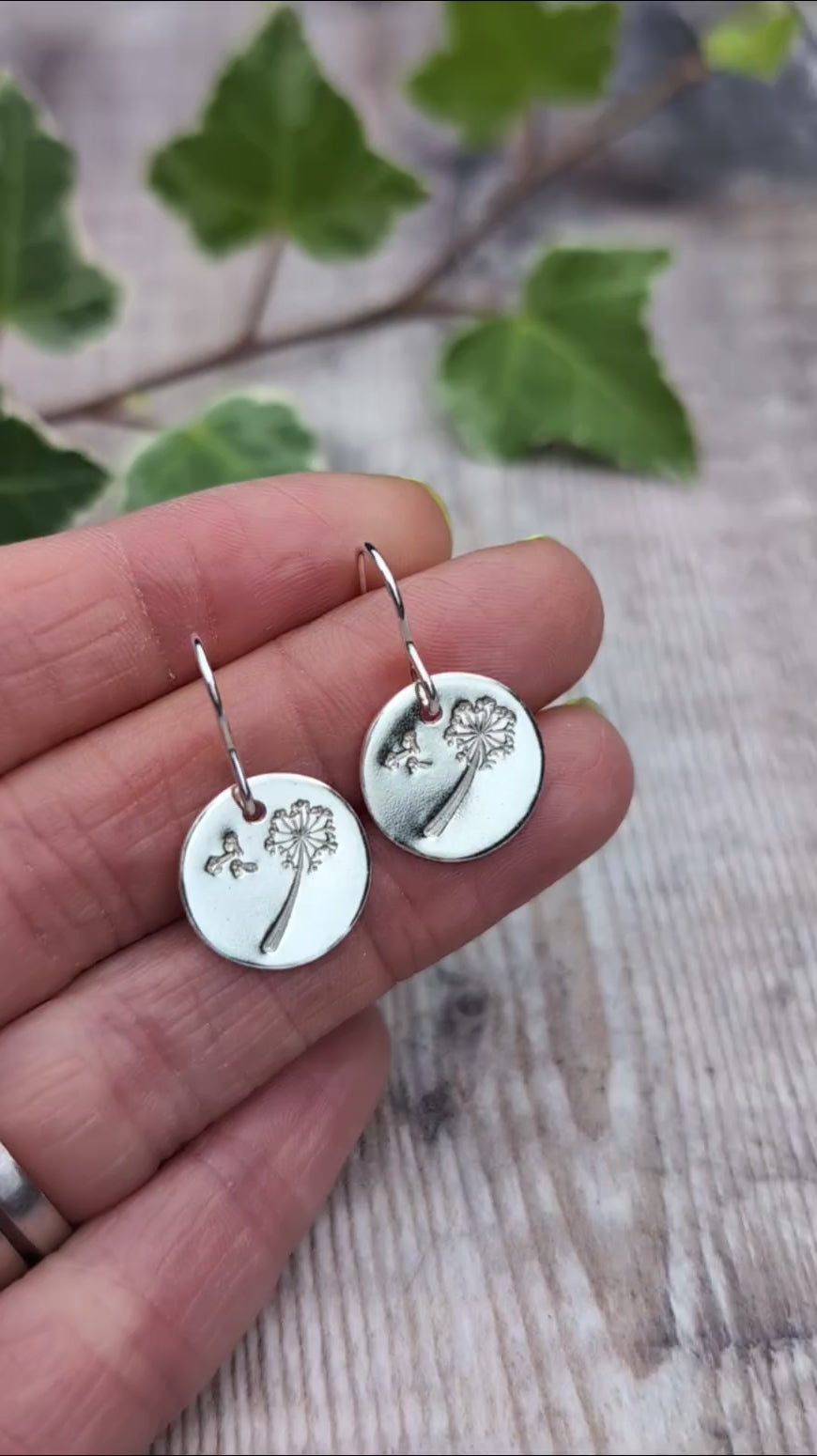 Video of Silver dandelion and wishes disc earrings held in a hand, showing the recycled Sterling Silver discs and stamped dandelion design.