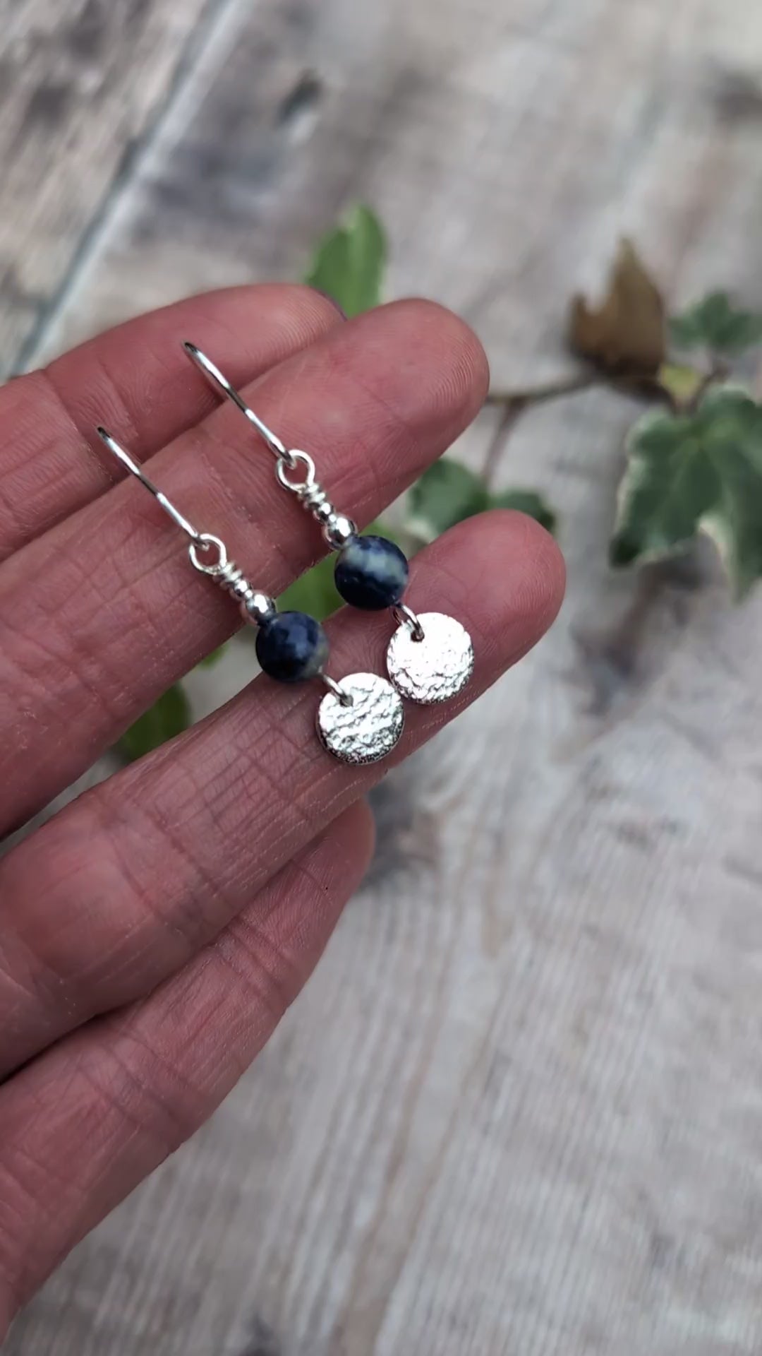 Video of blue sodalite and silver textured disc earrings resting on fingers, showing the natural blue and white patterns of the sodalite beads, textured sterling silver discs and silver bead details.