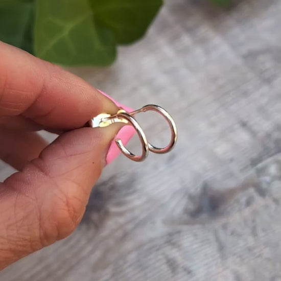 Close up of Silver small smooth hoop earrings handmade from recycled Sterling Silver displayed on fingertips.