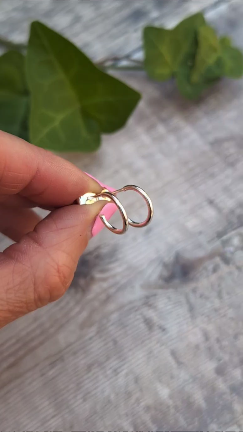 Close up of Silver small smooth hoop earrings handmade from recycled Sterling Silver displayed on fingertips.