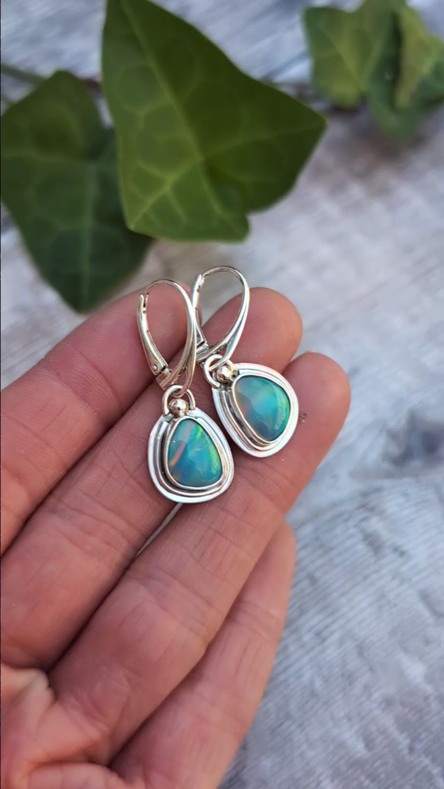 Turquoise Blue Aurora Opal Teardrop Earrings handmade from recycled Sterling Silver, photographed in the hand to show the colourful Aurora Opals and handmade details.