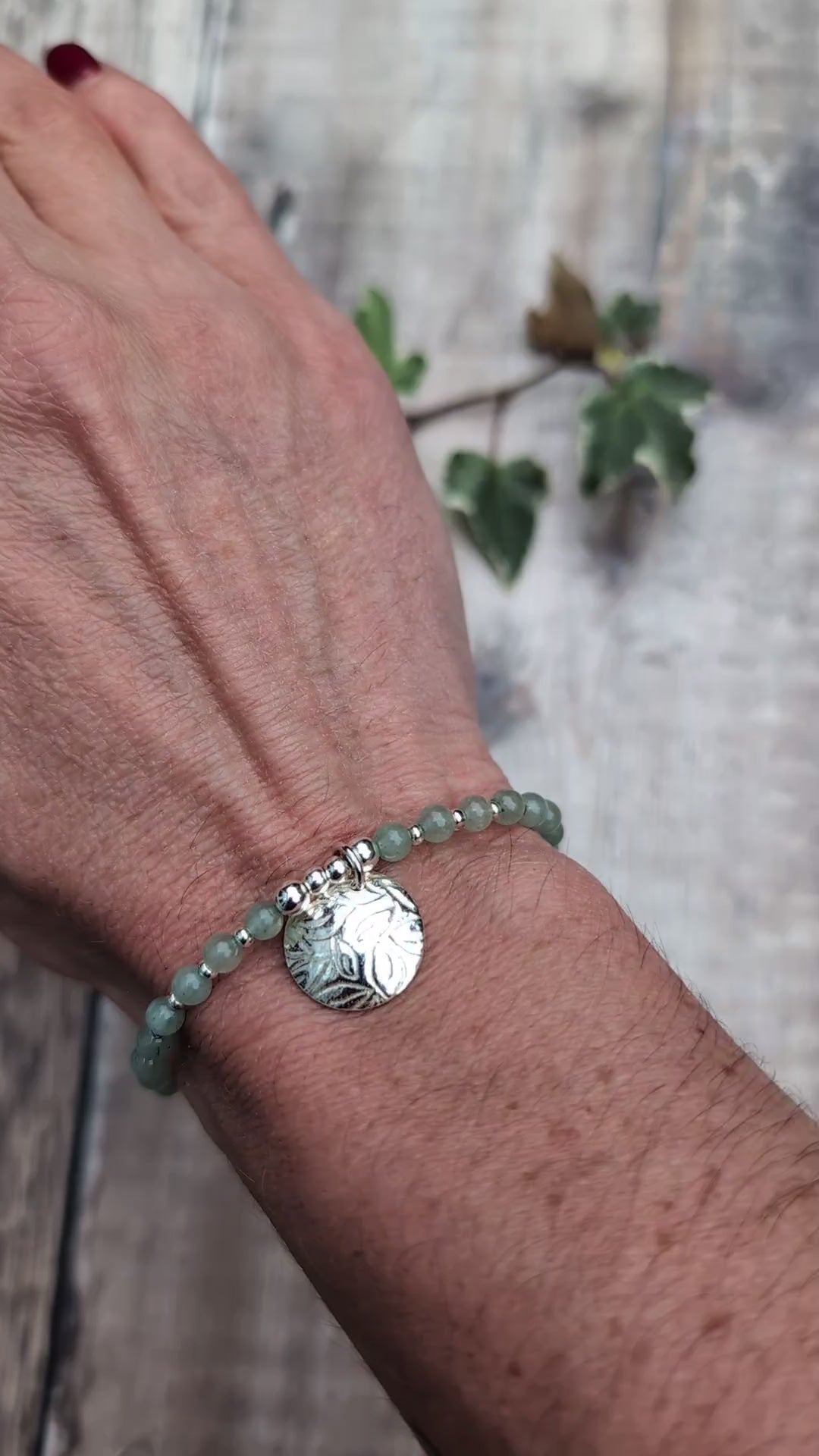 Video of Green aventurine and silver leaf disc bracelet worn on a wrist, showing the textured sterling silver leaf charm and small green aventurine beads separated by silver spacers.