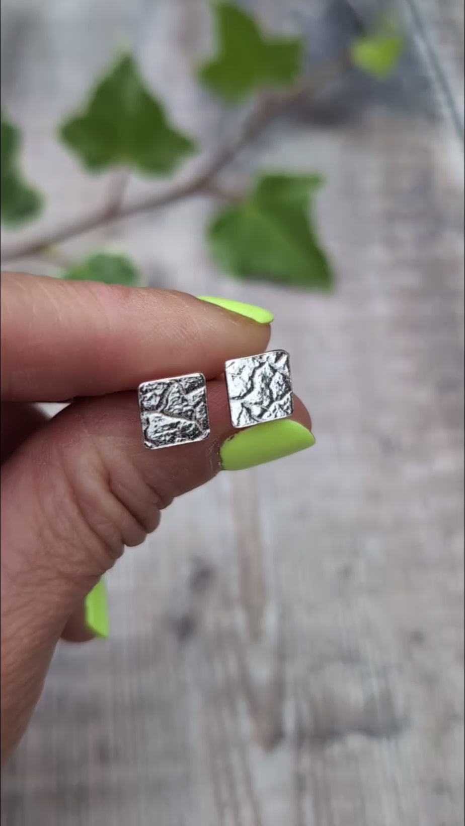 Video of Silver cracked earth pattern square stud earrings held on fingertips, showing their small square shape and textured silver surface.