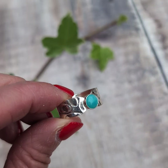 Video of silver oval patterned Amazonite wide band ring held between fingers, showing the blue Amazonite stone and patterned Sterling Silver band.
