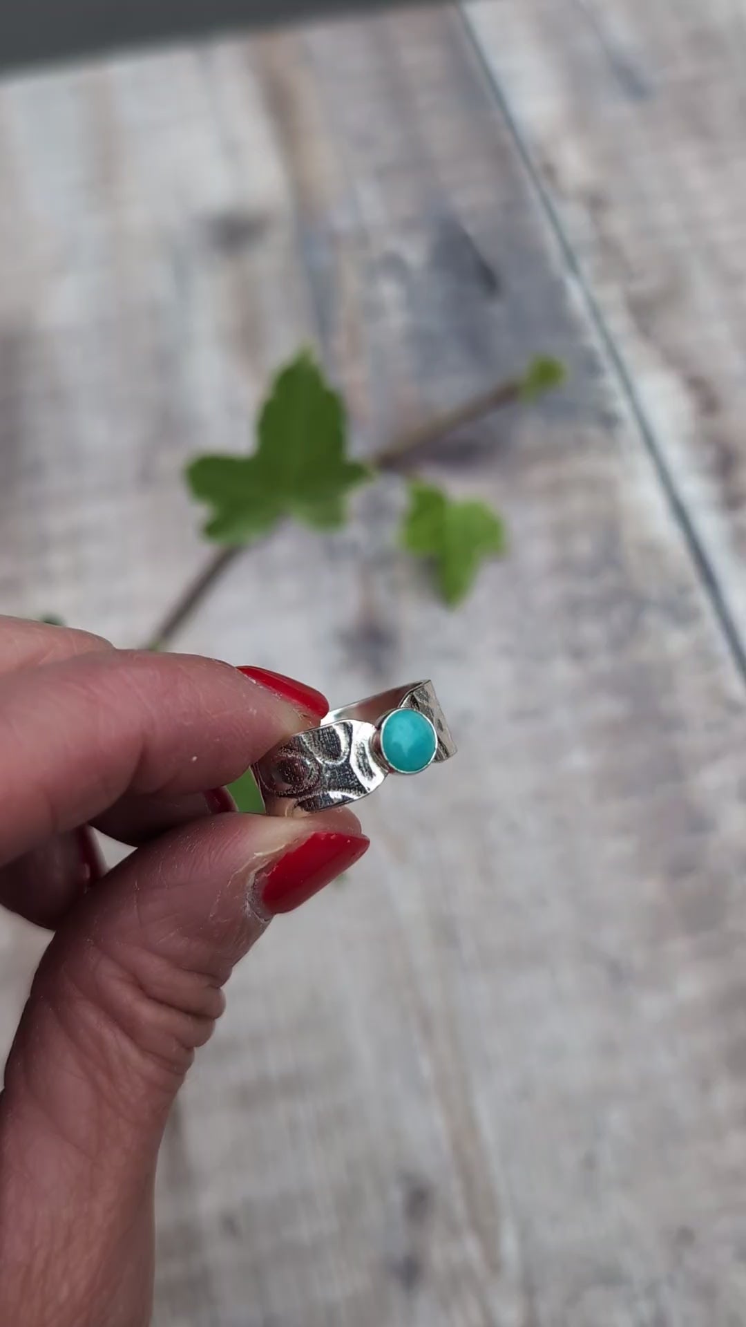 Video of silver oval patterned Amazonite wide band ring held between fingers, showing the blue Amazonite stone and patterned Sterling Silver band.