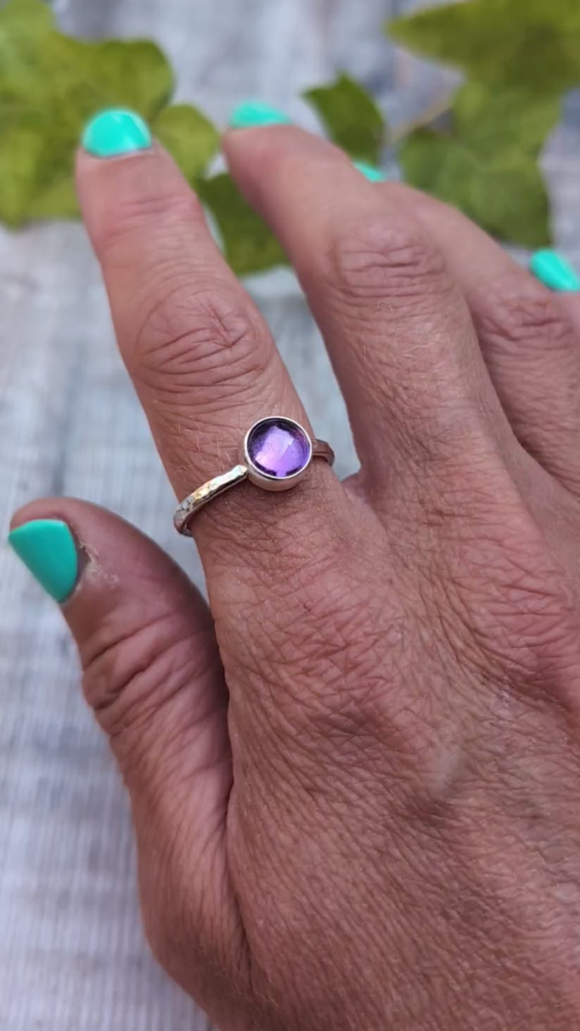 Amethyst ring size S handmade from recycled Sterling Silver, worn on a finger with the round purple Amethyst gemstone shown in natural light.