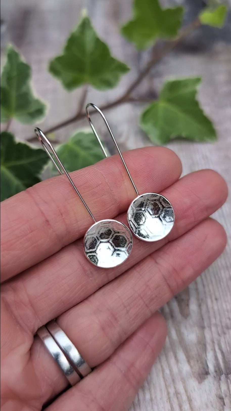 Video of Silver honeycomb long disc earrings handmade from recycled Sterling Silver, held in a hand to show their size and honeycomb texture.