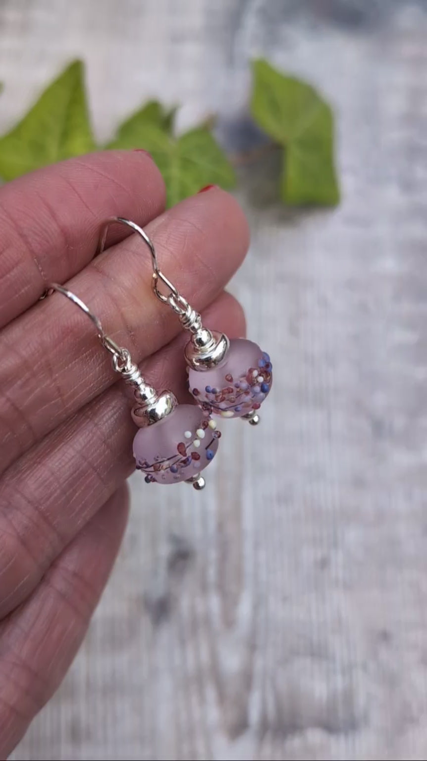 Video of Tropical Pink Lampwork Glass Earrings held in a hand, showing the frosted finish and colourful details on the handmade Lampwork beads.