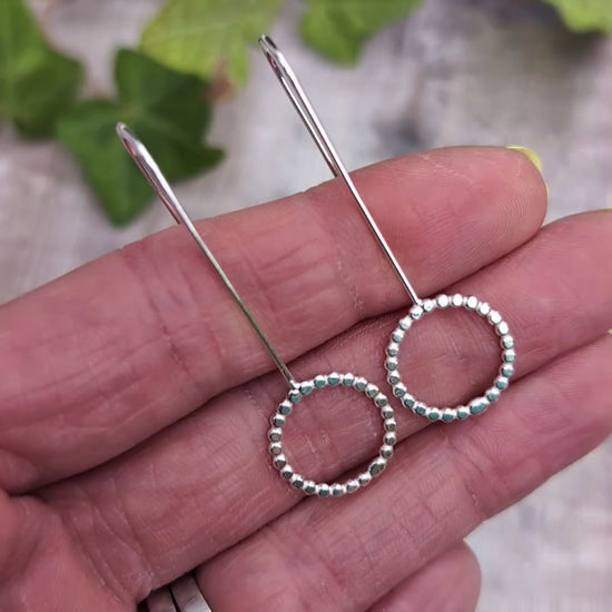 Video of Close up of silver beaded circle long earrings resting on a hand, showing the recycled Sterling Silver beaded circle detail.