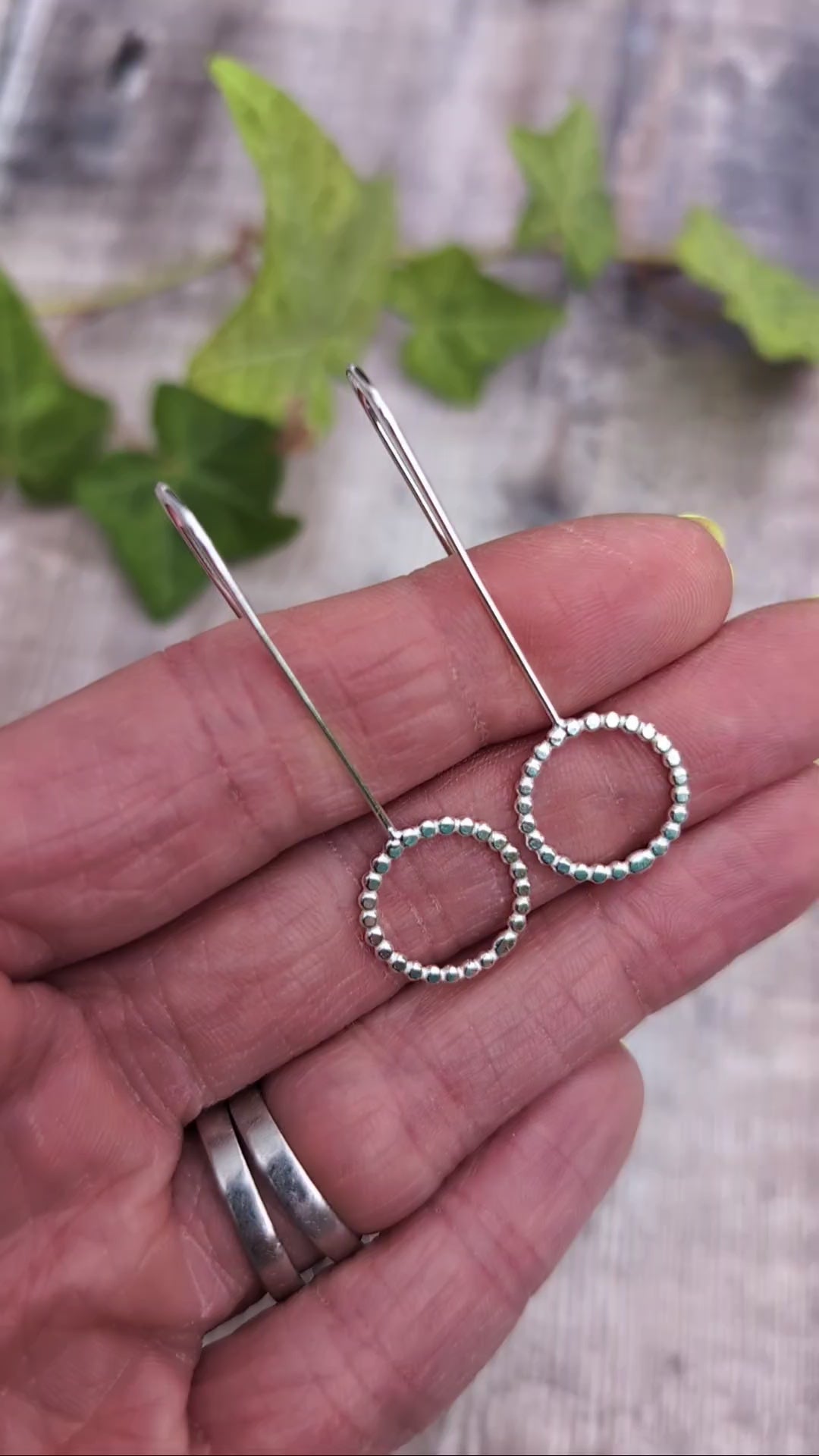 Video of Close up of silver beaded circle long earrings resting on a hand, showing the recycled Sterling Silver beaded circle detail.