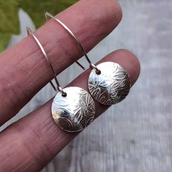 Close up of leaf pattern disc drop earrings handmade from recycled Sterling Silver highlighting the detailed leaf pattern and polished finish.