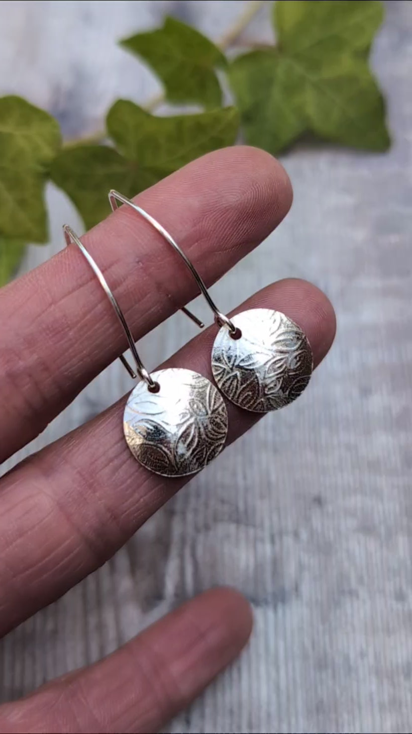 Close up of leaf pattern disc drop earrings handmade from recycled Sterling Silver highlighting the detailed leaf pattern and polished finish.