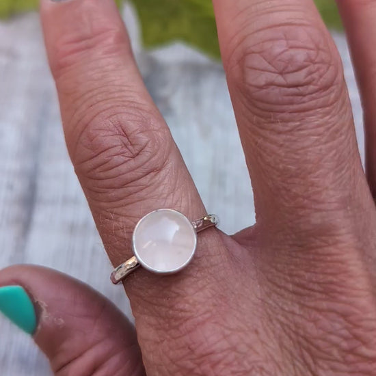 Rose quartz ring size R worn on a finger, handmade from recycled Sterling Silver with a polished round rose quartz gemstone in a bezel setting.