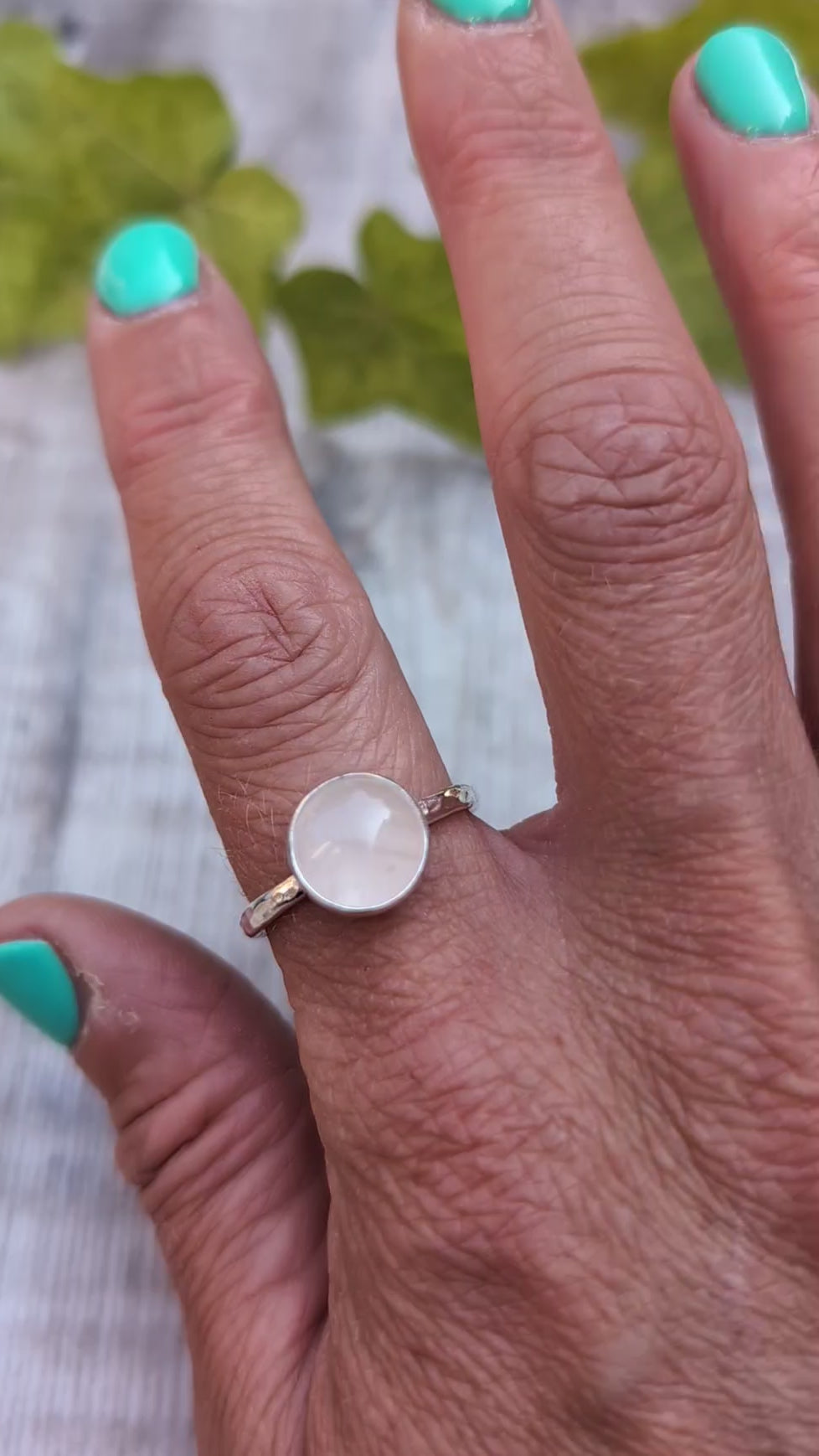 Rose quartz ring size R worn on a finger, handmade from recycled Sterling Silver with a polished round rose quartz gemstone in a bezel setting.