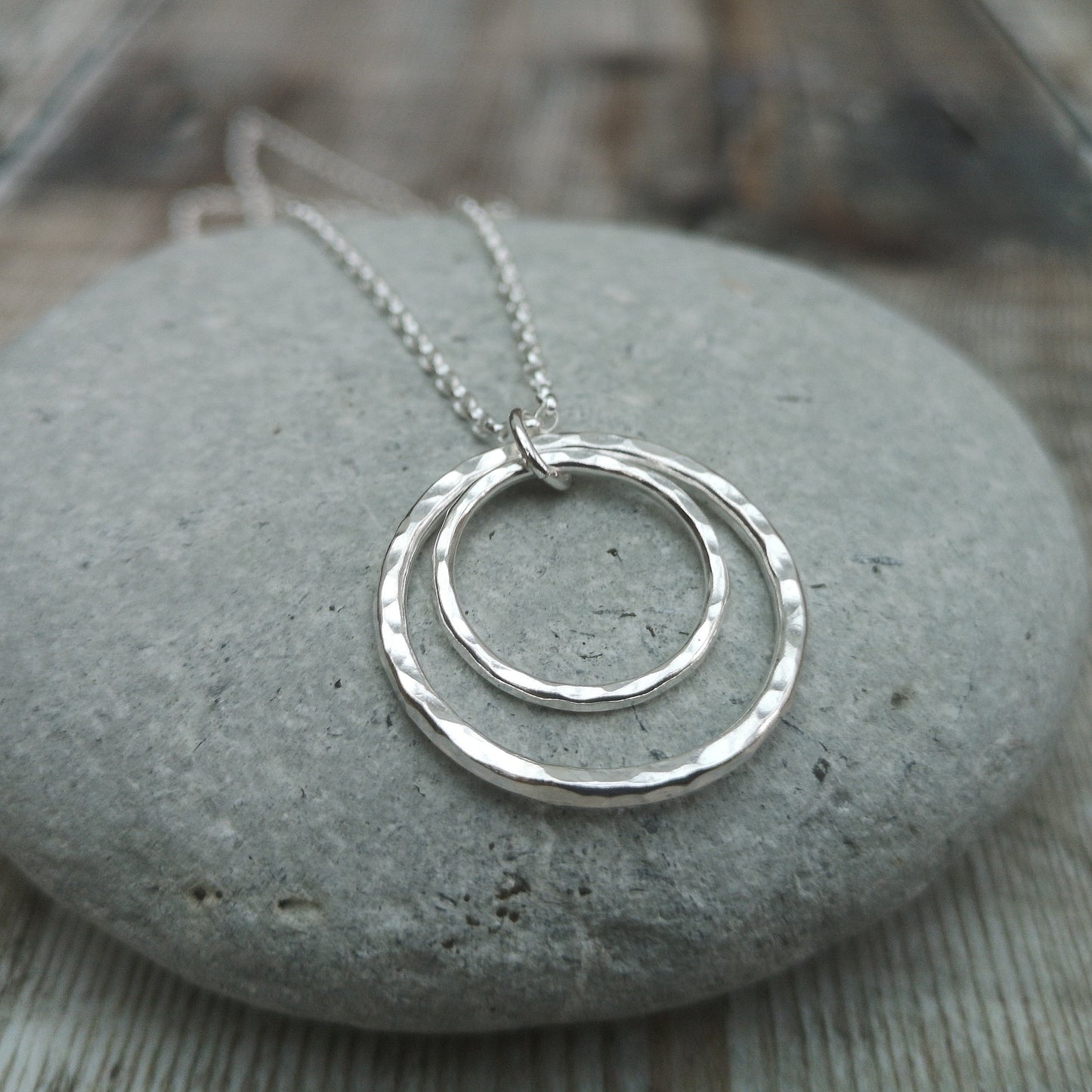 Pendant is one large and one small Sterling Silver open circles with hammered texture, attached to silver chain via small open circle link so that the smaller circle sits inside the larger circle.