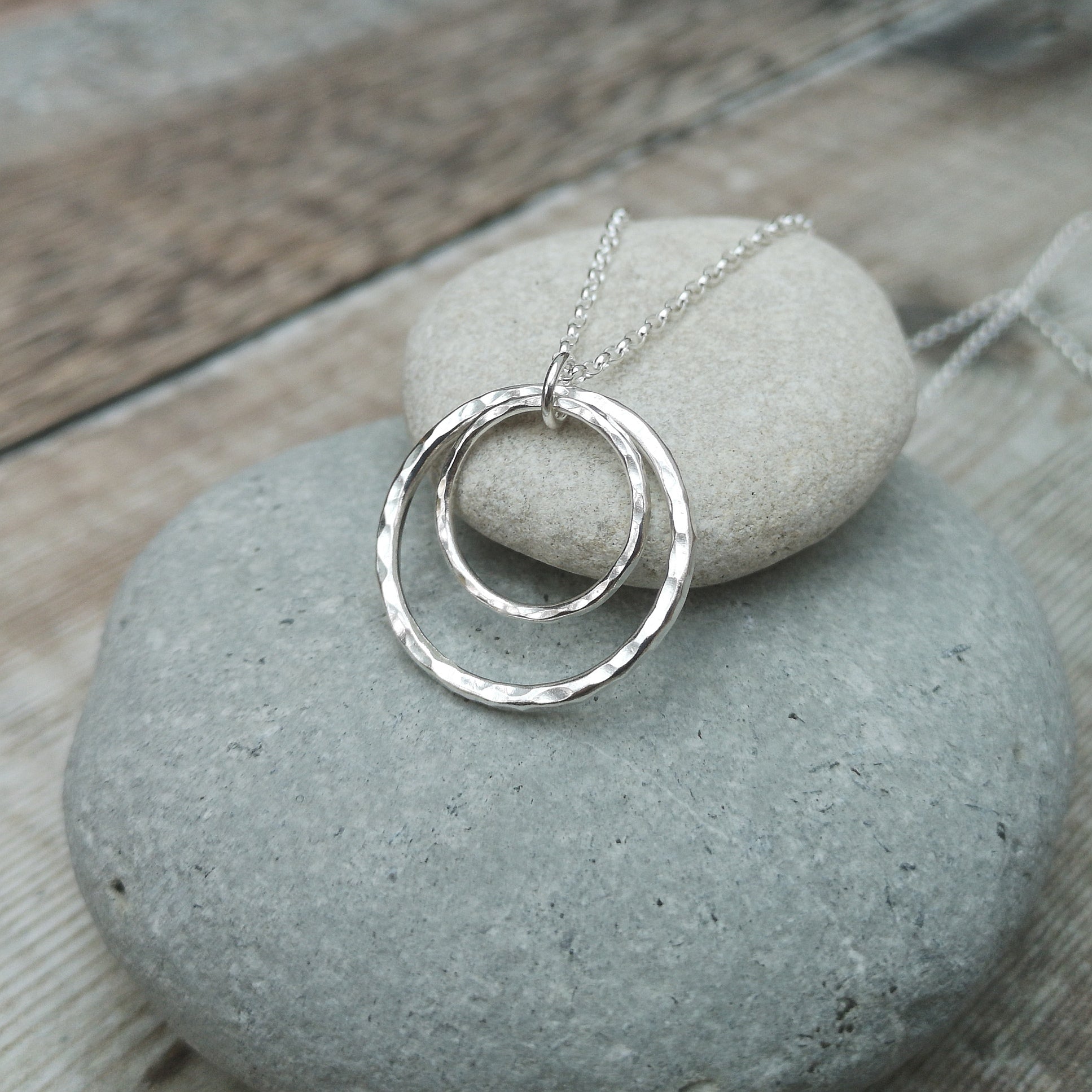 Pendant is one large and one small Sterling Silver open circles with hammered texture, attached to silver chain via small open circle link so that the smaller circle sits inside the larger circle.