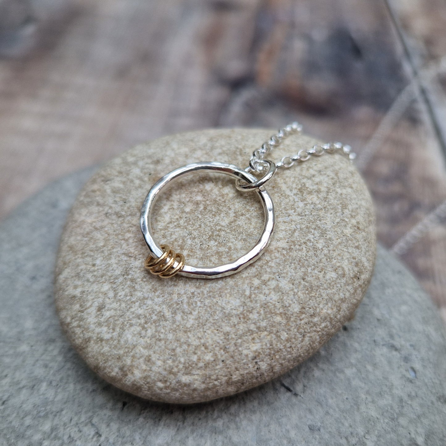 Each earring is a Sterling Silver hammered finish open circle suspended from silver earring wire. Three small gold open circles are threaded through the silver circle and move independently.