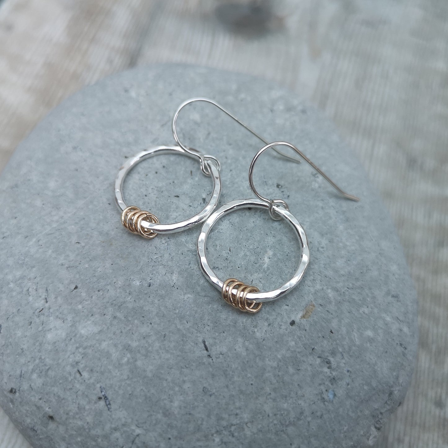 Each earring is a Sterling Silver hammered finish open circle suspended from silver earring wire. Four small gold open circles are threaded through the silver circle and move independently.