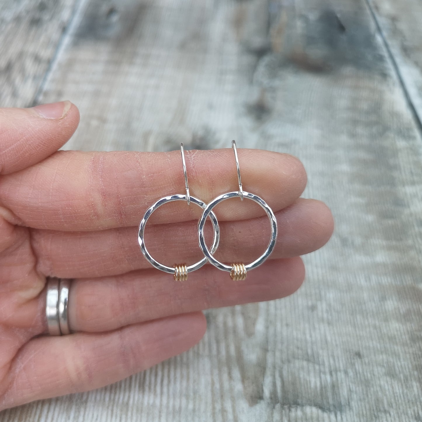 Each earring is a Sterling Silver hammered finish open circle suspended from silver earring wire. Four small gold open circles are threaded through the silver circle and move independently.