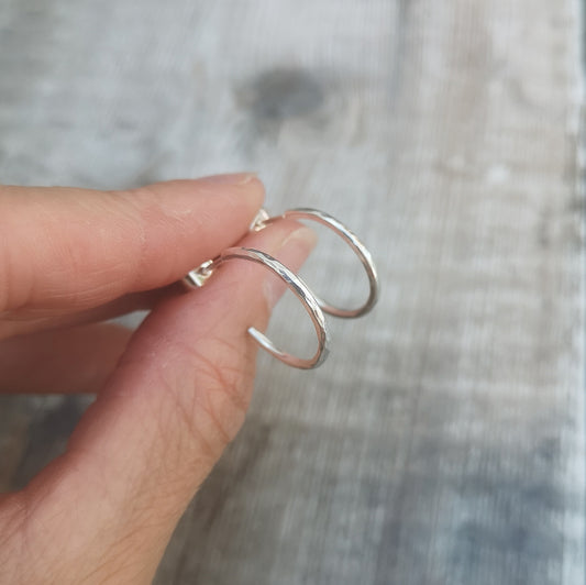 Each earring is a part silver hoop with hammered texture finish mounted on a silver stud bar.